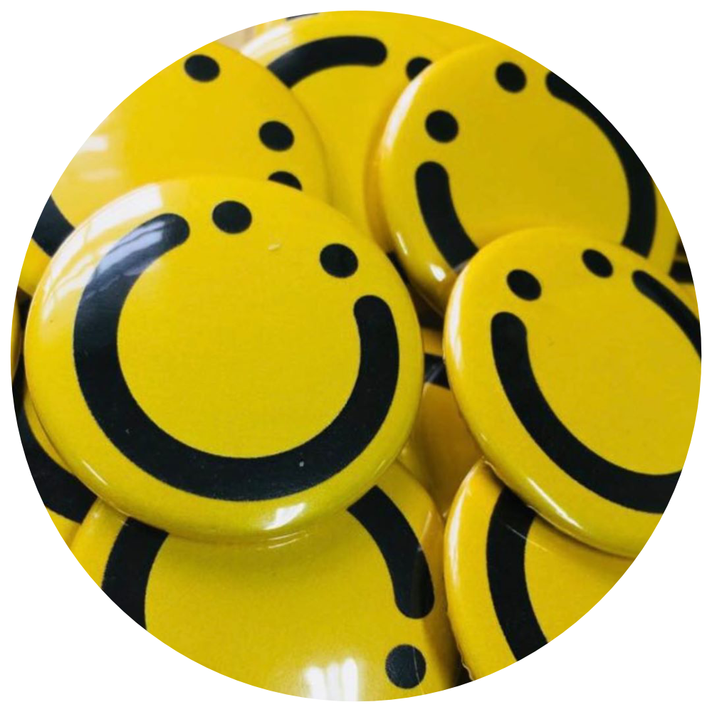 Round picture of yellow Roundhouse smiley faces badges on white and grey chequered background