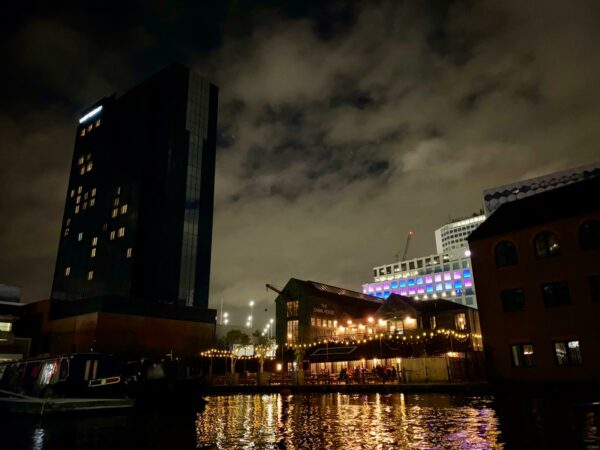 Picture of The Canal House Pub and Gas Street Basin taken at night from a kayak. The lights from the pub reflecting in the water and the sky above cloudy and grey.