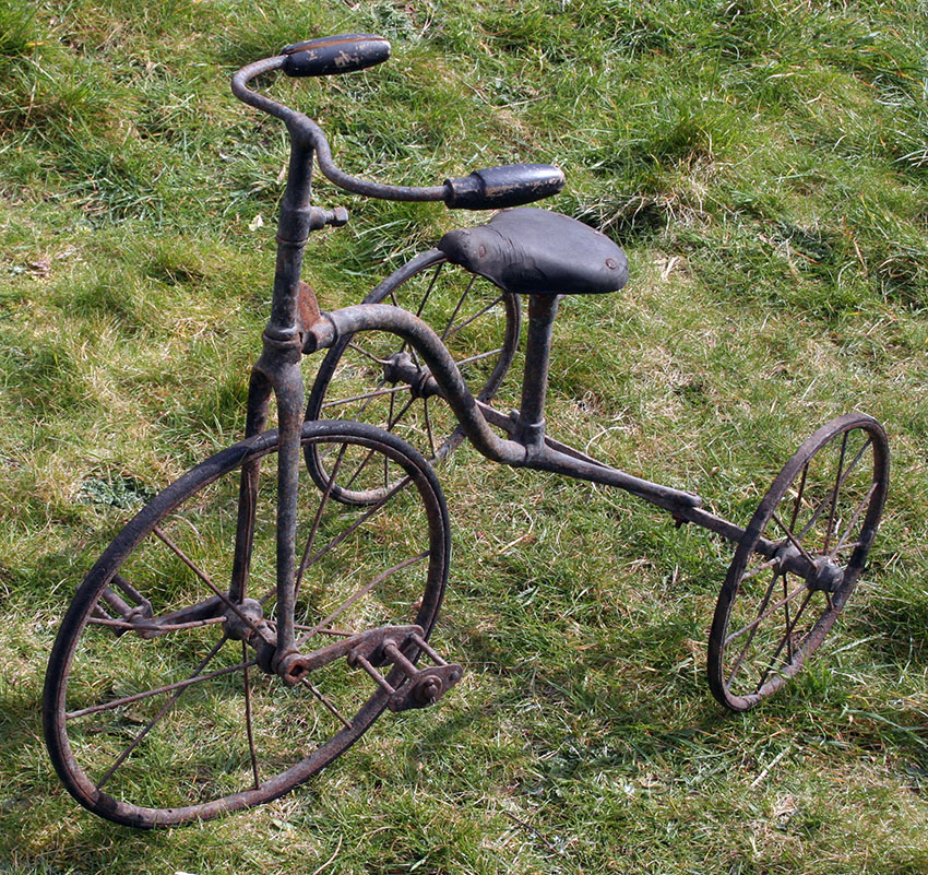 Old metal tricycle on grass