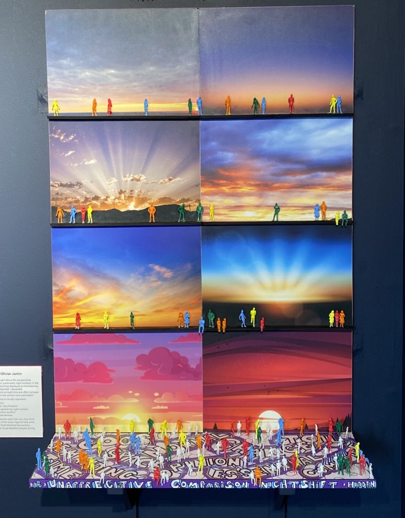 Picture of Hidden Giants by Oliver Jamin. A collage of eight pictures in bright colours depicting very colourful sky in the background and colourful figurines of people at the forefront of each picture. In front of the picture collage, at the base the picture extends tri-dimensionally into a small horizontal shelf filled with colourful figurines, similar to the ones in the pictures.