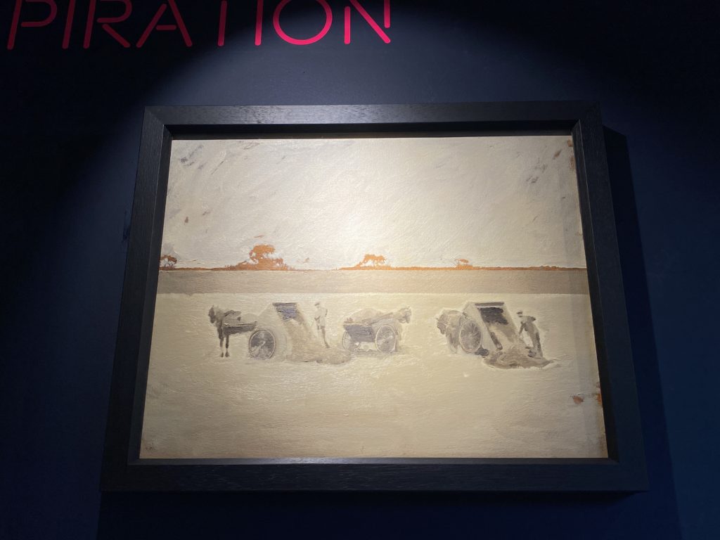 Picture of the Nightsoil painting by Ryan Hart. The painting is in light yellow, grey, white and black with occasional orange in the distance. It pictures three carts driven by horses. They are all stopped . The carts are filled of nightsoil and two workers unload the carts.