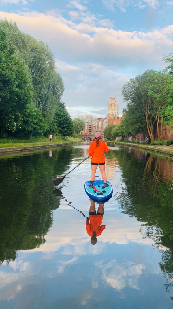 Paddleboarder on a sunny day on the Birmingham canal heading towards the city