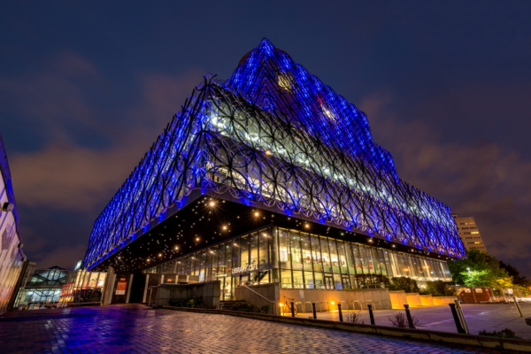 Picture of the Birmingham Library at night illuminated in blue
