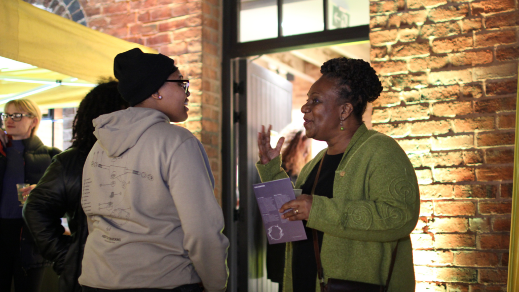 Two black people chatting at the evening launch of My Voice My Path Audio Tour.