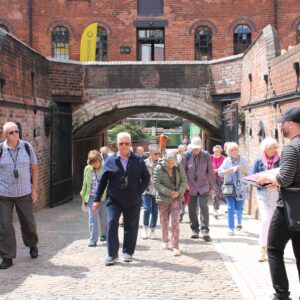 Large group taking part in an Introducing the Roundhouse private tour, in the Roundhouse courtyard on a sunny day