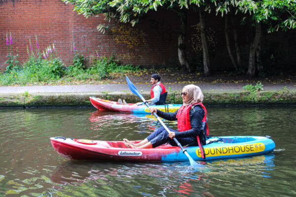 Two kayakers one man and one woman on the Bustling Birmingham tour. The lady is wearing a headscarf and sunglasses