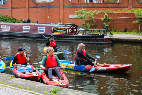 Group of kayakers with narrowboat moored in the background