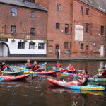 A group of Roundhouse kayakers posing for a photo on the canal in the Gas Street Basin