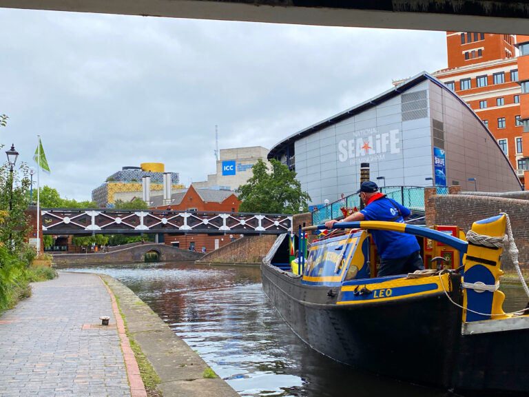 Heritage working boat named "Leo" being steered towards the Sea Life Centre in Birmingham