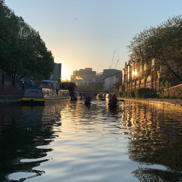 kayakers paddling along the canal away from the rising sun