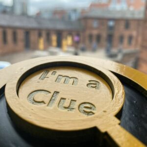 Circular wooden token with "I'm a clue" written inside a magnifying glass