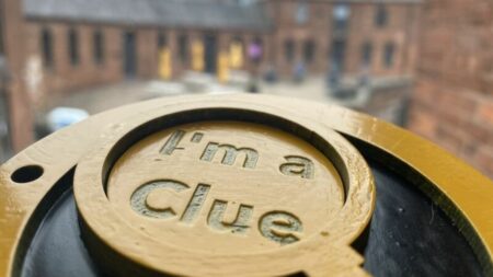 A landscape image showing a yellow wooden magnifying glass embossed with the words 'I'm a clue'.
