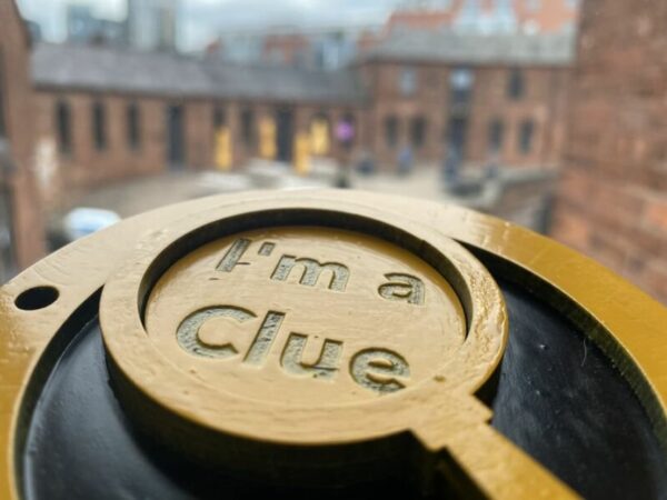 A landscape image showing a yellow wooden magnifying glass embossed with the words 'I'm a clue'.