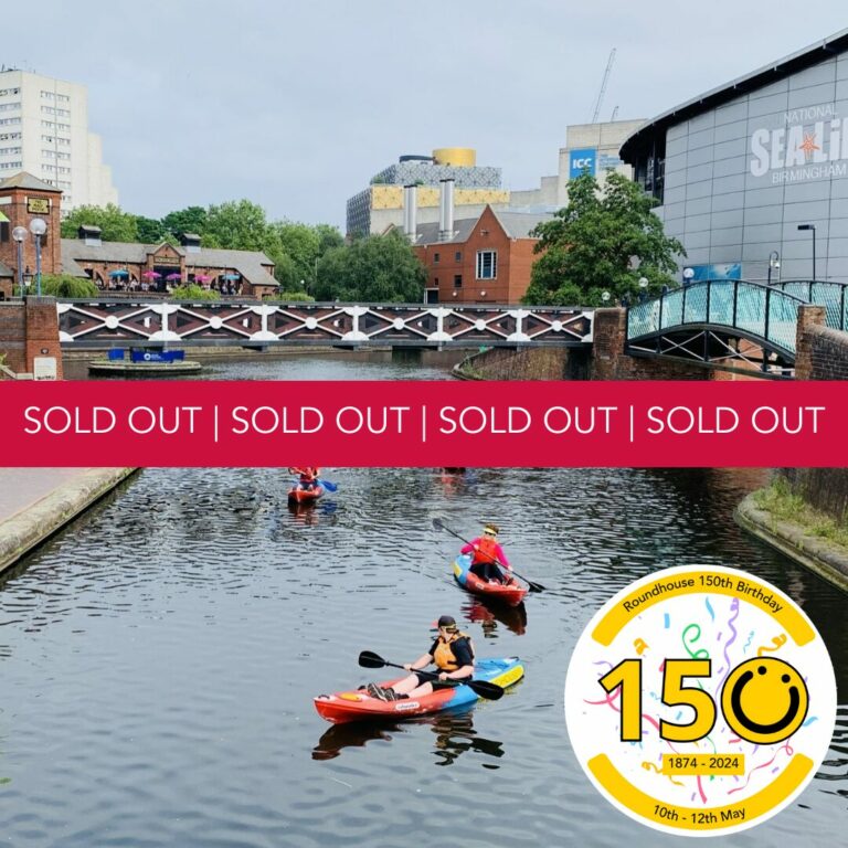 A square image showing six kayakers on canal water. The kayaks are red and blue. To their sides are towpaths. Above them is a black and white metal bridge. In the background and to the right of the image is a grey building with the words, 'SEA LIFE Centre' on and in the background is a yellow and grey building. In the bottom right of the image is a graphic logo with the number 150, the 0 of the logo is a yellow smiley face logo. The numbers 1 and 5 both have a black outline. Across the middle of the image is a red banner with the words, 'Sold Out' written. It is repeated 4 times.