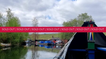 A landscape image showing a front of the end of a heritage working boat and a landscape in the distance. Across the middle of the image is a red banner with the words sold out on.