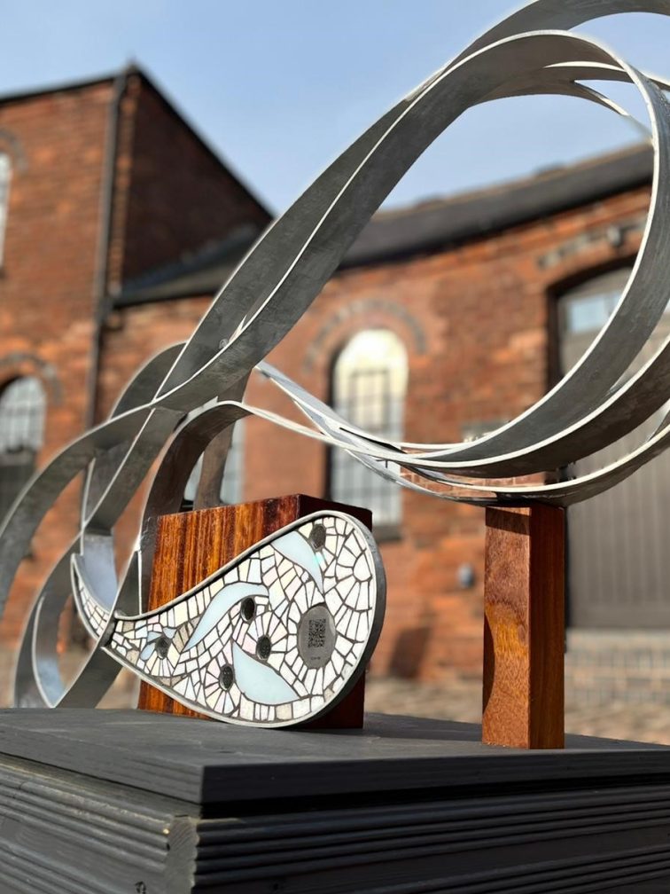 Picture of the Wander Water art object, in the Roundhouse Courtyard with the Roundhouse building in the background on a sunny day