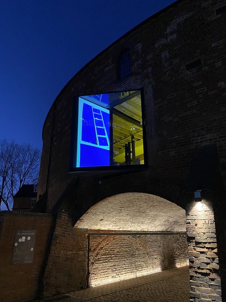 Picture of the Roundhouse window in the dark, illuminated with animations for the Workers of the Roundhouse window art