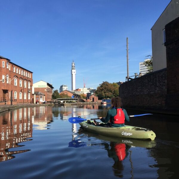 One person kayaking on Birmingham Canal with BT Tower in the distance